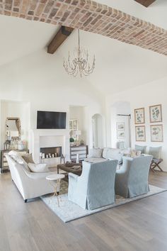 a living room with couches, chairs and a chandelier hanging from the ceiling