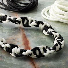 a black and white braided bracelet sitting on top of a table next to cords