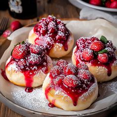 strawberry shortcakes covered in powdered sugar and topped with fresh strawberries on a plate