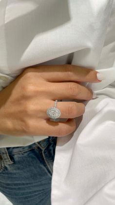 a woman's hand with a diamond ring on her left wrist, wearing jeans and a white shirt