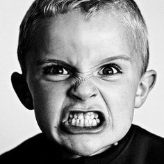 a black and white photo of a young boy with an angry look on his face