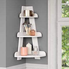 a white shelf in the corner of a room with various items on top of it