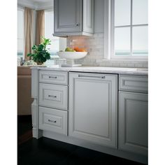 a bowl of fruit is on the counter top in this white kitchen with gray cabinets