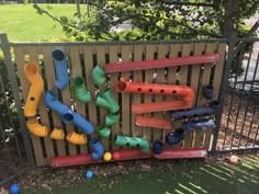 an outdoor play area with plastic pipes and balls on the ground in front of a fence