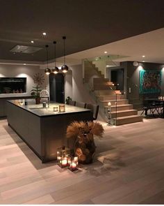 a large kitchen with candles on the counter and stairs leading up to an open floor plan