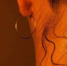 a close up of a woman's ear with large hoop earrings on top of it