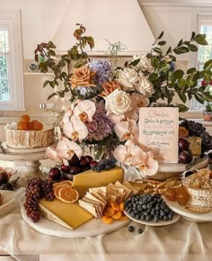 an assortment of cheeses, fruits and flowers on a table with a greeting card