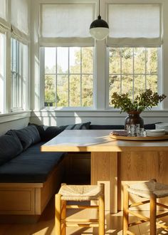 a kitchen table with two chairs and a bench in front of the window that overlooks trees