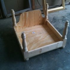 a wooden bed frame sitting on top of a floor next to a mirror and other furniture