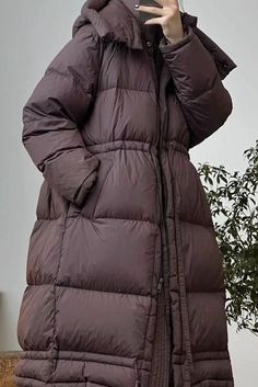 a woman is taking a selfie with her cell phone while wearing a long coat