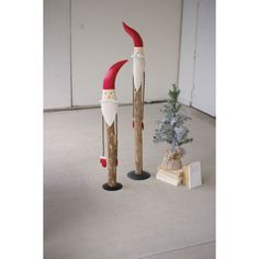 two wooden poles with santa's hats on them and a small christmas tree in the background