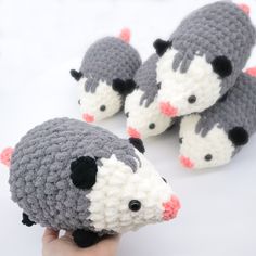 a hand is holding three small crocheted mice in grey and white, with black noses