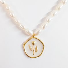 Indulge in the beauty of the Tulip Coin Pendant Pearl Necklace, a meticulously handcrafted piece featuring an enamel tulip flower delicately placed on thick gold-plated brass. The intricate detailing of the enamel work brings the tulip to life, while the lustrous seed pearl necklace adds a touch of elegance and sophistication. This necklace is a perfect fusion of artistry and quality, showcasing the beauty of nature and craftsmanship in a timeless piece that will be treasured for years to come. MATERIALS: Metal: Gold-plated Brass Pendant: Handmade Enamel Pearls: Natural Freshwater Pearl DIMENSIONS Natural stone & Pearl sizes may vary slightly. Necklace Length: 14.2 inches + 4.3 inches extension Pendant Length: 0.9 inches Width: 0.8 inches PROCESSING & SHIPPING All of my pieces are shipped Handmade Gold Enamel Necklaces, White Medallion Pearl Necklace Gift, Gold Mother Of Pearl Flower Pendant Jewelry, Gold Mother Of Pearl Necklace For Gift, Gold Flower-shaped Enamel Jewelry, Gold Enamel Flower Jewelry, Gold Enamel Necklace For Wedding, Flower Shaped Pearl Charm Jewelry Gift, Flower Shaped Pearl Charm Necklace Gift