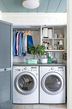 a washer and dryer sitting in front of a shelf with clothes on it