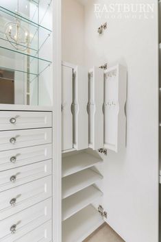 an empty closet with white drawers and glass shelves