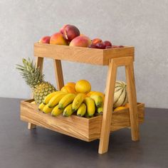 a wooden fruit stand with bananas, pineapples and peaches on it's sides