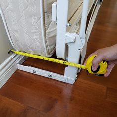 a person holding a measuring tape near a bed with a mattress on the bottom bunk