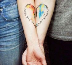 two people are holding hands with tattoos on their arms that say love is in the air