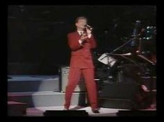 a man in a red suit singing on stage