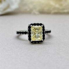 a fancy ring with a yellow diamond surrounded by black and white diamonds on a table