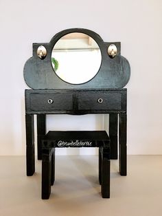 a black vanity with a mirror on top of it next to a stool and window