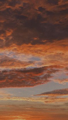 an airplane is flying in the sky at sunset or dawn with orange and blue clouds