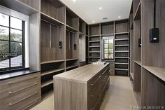 a large walk in closet with lots of shelves and drawers on the wall, along with an open window