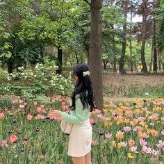 a woman standing in the middle of a field of flowers