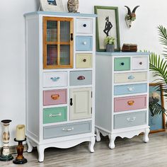 two tall white cabinets with multicolored drawers on each side and an owl figurine sitting on top