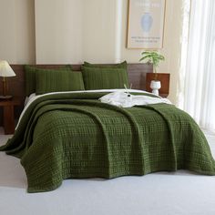 a bed with green bedspread and pillows