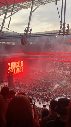 a stadium filled with lots of people watching a game on the big screen and red lights