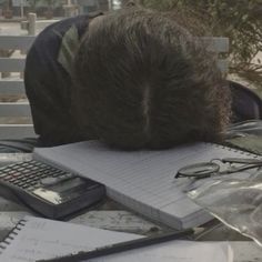 a man sleeping on top of a pile of papers next to a calculator