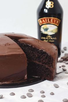 a chocolate cake on a plate with a bottle of bailey's in the background