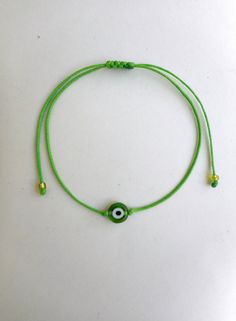 Lime green evil eye bracelet with glass bead and waxed polyester cord.Durable and water resistant Looks great worn by itself or stacked with other string bracelets!  Super lightweight, and comfortable enough to sleep in! Mix and match your bracelets for a fun, customized look! This lime green macrame string bracelet is handmade, wax coated polyester string. It has a flat eye bead and 2 little glass seed beads at ends.  Bracelet has an adjustable pull closure.  To put your bracelet on, you simply Evil Eye String Bracelet, Rat Jewellery, Green Evil Eye, Green Macrame, Micro Macrame Jewelry, Thread Bracelet, String Bracelets, Thread Bracelets, Vegan Gifts