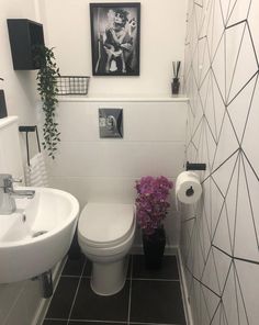 a white toilet sitting next to a sink in a bathroom under a picture on the wall