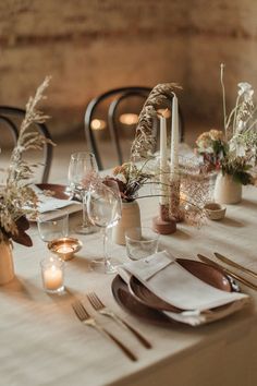 the table is set with candles, plates and napkins for dinner guests to enjoy