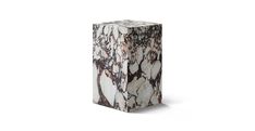 a white and brown marble vase sitting on top of a table next to a wall