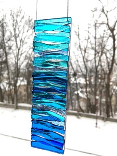 a wind chime hanging from a window with trees in the background