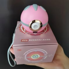 a hand holding a pink and white object on top of a box with an mp3 player in it