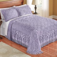 a bed with purple bedspread and white pillows