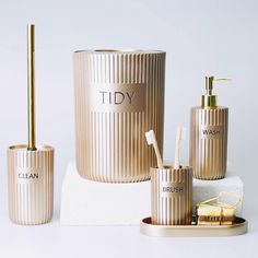 three gold bathroom accessories including soap dispenser, toothbrush holder and cup