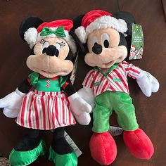 two mickey and minnie mouse stuffed animals sitting next to each other on a wooden table