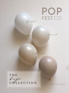 three white balloons sitting on top of a table next to the words pop fest co