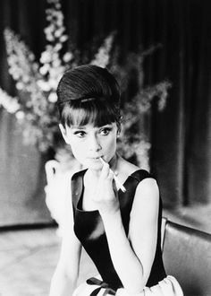 a black and white photo of a woman sitting on a chair with her hand under her chin