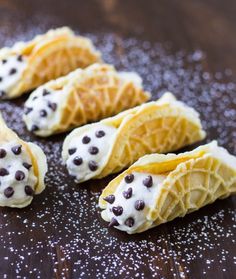 three waffles with chocolate chips and cream filling on a wooden surface, one is cut in half to show the inside