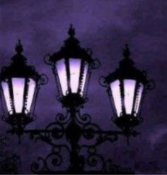 an old fashioned street light is lit up against the night sky with purple hues