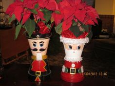 two decorated vases with poinsettias and santa hats on top of them