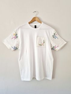 New design to my store ✨️  A plain white 100% cotton classic tshirt in a unisex size Large Unique modern tshirt with added Vintage linen fabrics.  The sleeves are made using a Vintage 1950s linen tablecloth that has delicate hand embroidered designs The patch on the front of the Tshirt is also Vintage 1950s embroidered linen  The tshirt itself is a very soft light cotton  Perfect for the warmer months with shorts or a skirt and then equally perfect for the cooler months under a Cardigan or jacke Upcycle T Shirts, Modern Tshirt, Upcycled Tshirt, Upcycle Tshirt, Embroidered Designs, Linen Fabrics, Recycled T Shirts, Embroidered Linen, Vintage Linen