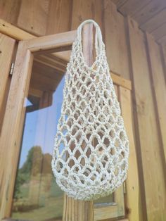 a white crocheted bag hanging from a wooden pole