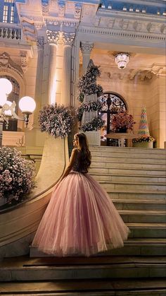 a woman in a pink dress standing on some stairs